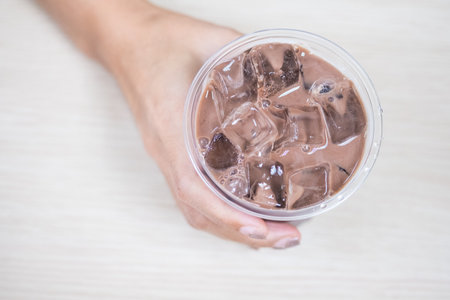 Hand on iced chocolate cocoa on wood tableの写真素材