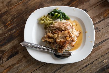 Braised pork leg placed cooking rice with a side dish of pickled vegetables and green kale. Thai called Khao Kha Mooの写真素材