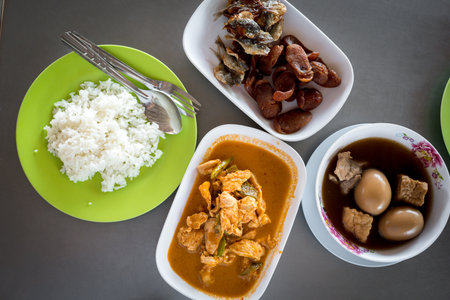 Various of Thai meals such as pork panang curry, stewed eggs eating with rice on wood table. Top viewの写真素材