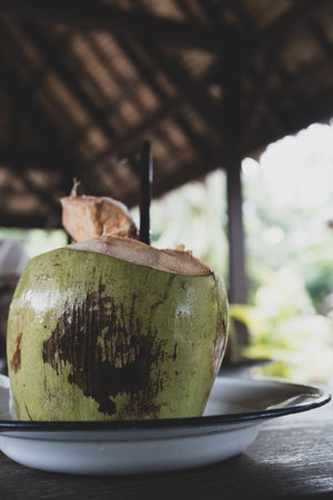 Fresh green coconut water with straw served on dish. Healthy drinkの写真素材