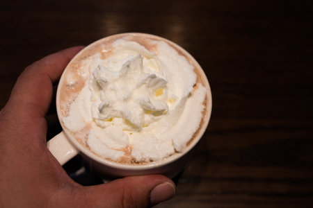 A glass of hot mocha with whipped cream in hand. Close upの写真素材