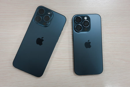 Bangkok, Thailand - December 7, 2023 : iPhone 15 Pro Max and iPhone 15 Pro is blue Titanium to compare on wood table. A tech smartphone modern design and the latest iPhone.のeditorial素材