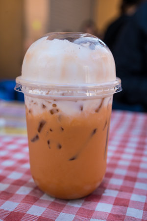 A glass of Thai iced milk tea with ice in a plastic cup. Close upの写真素材
