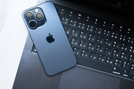Bangkok, Thailand - December 12, 2023: iPhone 15 pro blue titanium placed on keyboard of MacBook Pro, M3 Max 2023, Space Black colourのeditorial素材