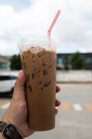 A long glass of iced mocha in hand.の写真素材