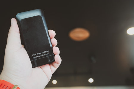 Hand holding black queue paging Wireless Calling System for restaurants, coffee shops or cafeの写真素材