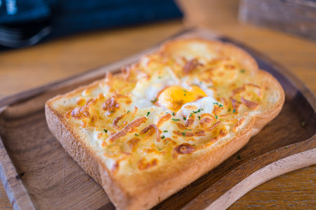 Cheesy baked egg toast served on wooden board, close upの写真素材