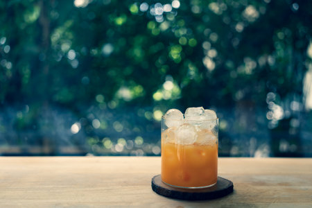 A glass of orange juice with ice on wood table. Close upの写真素材