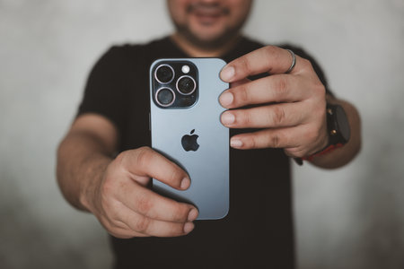 Bangkok, Thailand - December 15, 2023 : A young man taking a photo with iPhone 15 pro features, triple-lens camera setup with 5x optical zoom.のeditorial素材