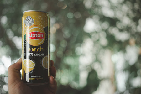 Bangkok, Thailand - December 15, 2023 : Man hand holding aluminium can of a Lipton sparkling lemon no sugar against nature backgroundのeditorial素材