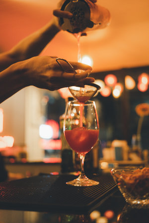 Barman is making cocktail on the bar counter at night club.の写真素材