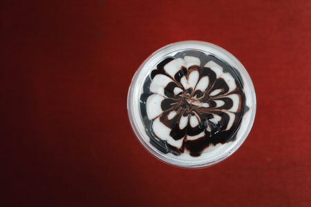 Top view of iced mocha coffee latte art chocolate flower shape spiral glass on red backgroundの写真素材