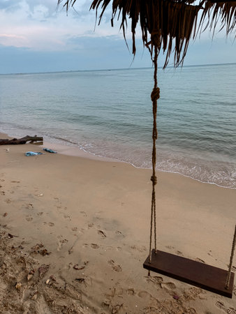 Wooden swing on the beach with sea view, relaxing by the sea, tropical climate. Take a photo by smart phoneの写真素材