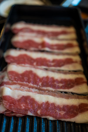 Thinly sliced beef served on a black tray used for sukiyaki and shabu Close upの写真素材