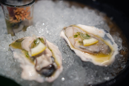 Fresh oysters platter with sauce and lemon on crushed ice. Opened oysters ready to eatの写真素材