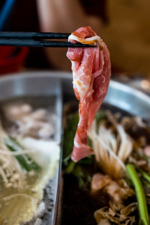 Holding sliced beef meat by chopsticks eat shabu in lunch timeの写真素材