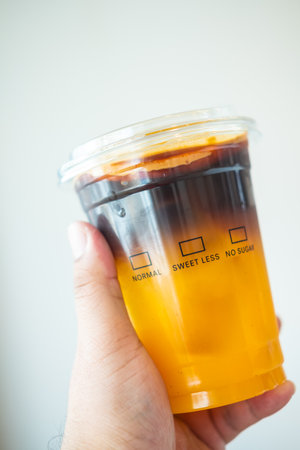 Hand holding coffee iced americano mix with orange juice. Benefit from coffee and orangeの写真素材