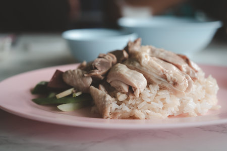 Steamed rice topped with boiled chicken and offal chicken on pink dish. Close upの写真素材