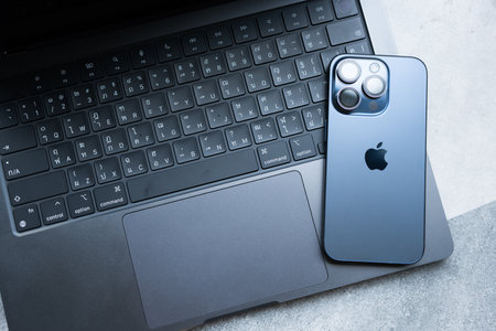 Bangkok, Thailand - December 24, 2023: iPhone 15 pro blue titanium placed on keyboard of MacBook Pro, M3 Max 2023, Space Black colourのeditorial素材