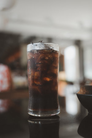 A glass of soft drink and ice with white straw at restaurantの写真素材