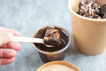 Delicious chocolate brownie with almond slices topping doing dipping melted chocolateの写真素材