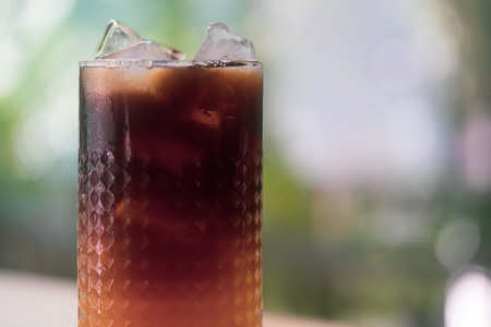 Glass of iced coffee with orange juice on nature background.