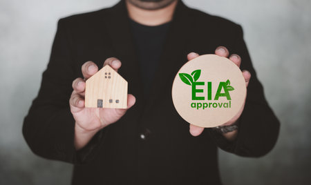 Businessman holding the approval EIA and home model. Environmental Impact assessment is the assessment of the environmental consequences of a plan before the decision.の写真素材