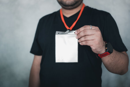 Man at an exhibition or conference showing a blank security identity name card on a lanyard, blank id card badge. Badge name tag, lanyard. Conference, event, convention vip passの写真素材