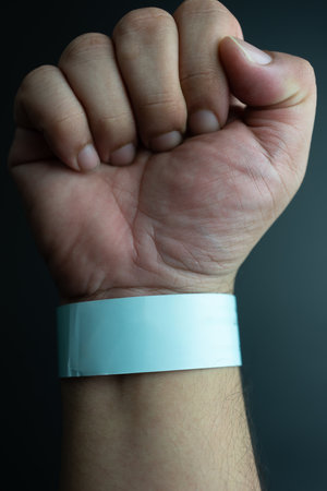 Blue paper wristband mockup on persons arm. Empty adhesive bangle wristlet sticker on male hand, blue paper bracelet, check tape, event ticket conceptの写真素材
