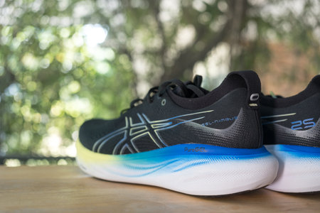 Bangkok, Thailand - January 7, 2024 : Running shoes from the brand Asics on wood table. ASICS Running Shoes Gel Nimbus 25 WIDEのeditorial素材