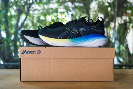 Bangkok, Thailand - January 9, 2024 : New asics sneakers, ASICS Running Shoes Gel Nimbus 25 WIDE placed on a cardboard box on wood tableのeditorial素材