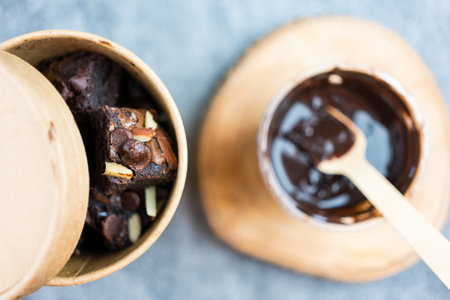 Delicious chocolate brownie topped with almond and chocolate chip in a paper brown bowl box.の写真素材