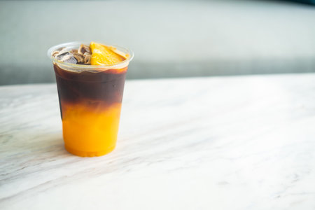 Iced americano mixed orange juice in plastic cup on table.の写真素材