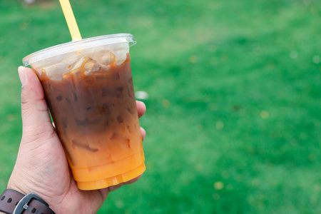 Take away plastic cup of iced Americano fusion with fresh orange fruit on man hand.の写真素材