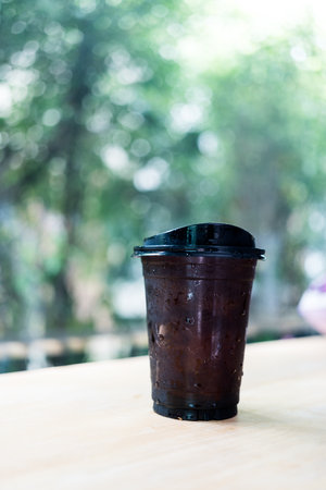 Iced black coffee or Americano coffee in takeaway glass against nature backgroundの写真素材