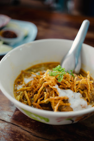 A bowl of curried noodle soup Thai called Khao soi with pork and topping coconut milk. Thai food.の写真素材