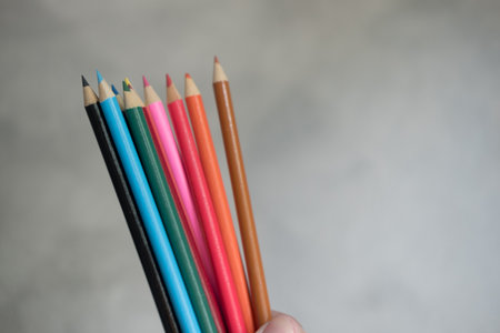 Hands catching or holding a stack of wooden multi colored pencils. Selective focusの写真素材