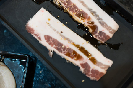 Fresh bacon raw sliced was served for Sukiyaki and Shabu or Yakiniku restaurant which it put on black tray.の写真素材