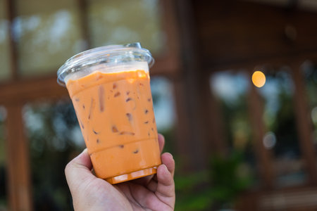 Man holding a plastic cup of iced Thai milk tea. Summer drinks with iceの写真素材