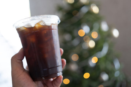 Ice black coffee in man hand and bokeh lighting in christmas holidaysの写真素材