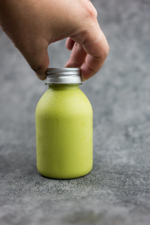 Man picking a bottle of healthy avocado smoothie blended with yogurt or milk. Smoothie for a healthy dietの写真素材
