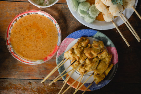 Grilled pork satay in skewer served with peanut sauce or sweet and sour sauce and many appetizers such as grilled meatballsの写真素材