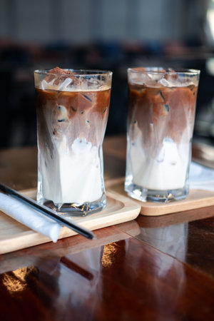 Two iced Mocha coffee two layers fresh milk and espresso short on wooden table at cafe. Refreshing summer drink concept, selective focusの写真素材