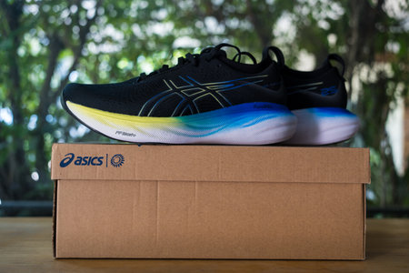 Bangkok, Thailand - January 31, 2024 : New asics sneakers, ASICS Running Shoes Gel Nimbus 25 WIDE placed on a cardboard box on wood tableのeditorial素材