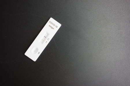 Rapid Antigen Test kit with Positive result during swab COVID-19 testing on a black background.の写真素材