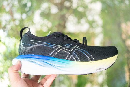 Bangkok, Thailand - February 5, 2024 : Man hand holding a shoe of ASICS Running Shoes Gel Nimbus 25 WIDE. Shoe sport sneakers for joggingのeditorial素材