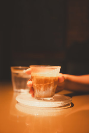 A glass of coffee with milk called Dirty coffee one of the famous coffee menu with woman handの写真素材