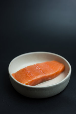 Portioned raw slices of fresh raw salmon on dish prepare to cook.