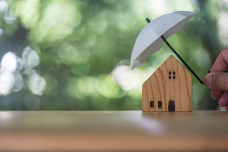 Home and real estate insurance ideas, Man use white small umbrellas and wood homes. Home insurance for upcoming losses and fires building fire insurance. Insurance is risk controlの写真素材