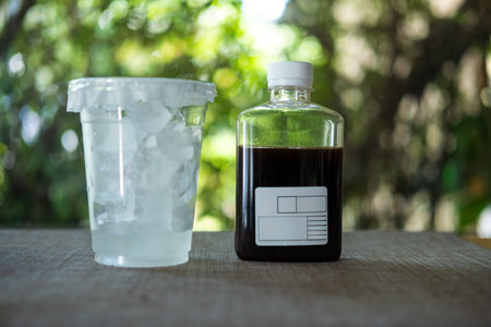 Cold brew coffee in a glass bottle and ice in glass for take away against nature background.の写真素材